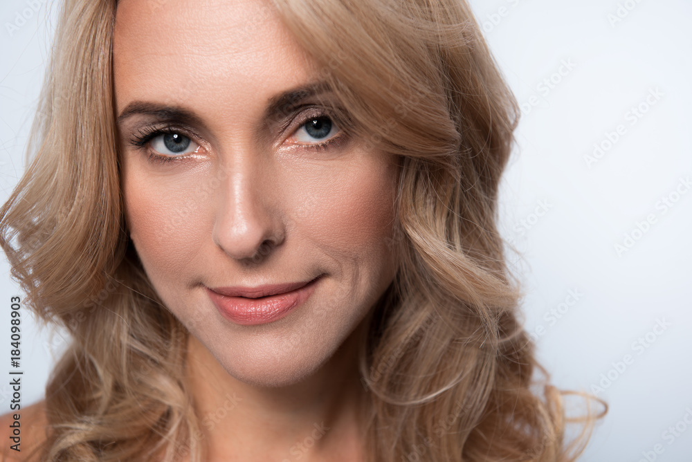 Close-up portrait of gorgeous charming middle-aged woman with fresh skin and long hair. She is looking at camera with slight smile. Isolated background Close-up portrait of gorgeous charming middle-aged woman with fresh skin and long hair. She is looking at camera with slight smile. Isolated background