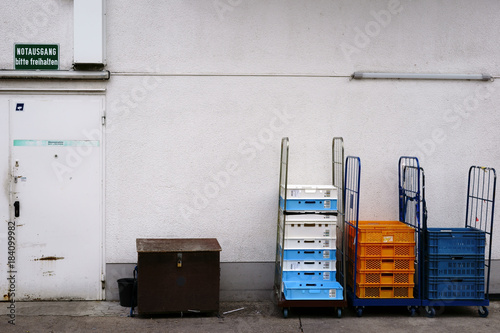 Paletten an der Warenannahme  / Eine Warenannahme am Hintereingang eines Lebensmittelladens mit Kisten und Paletten auf rollbaren Ladeflächen. photo