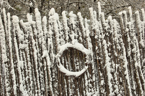 Tree branch fence with wreath covered with snow