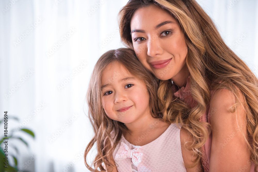 Portrait of happy asian mother and daughter cuddling with love. They are looking forward with gentle smile. Copy space Portrait of happy asian mother and daughter cuddling with love. They are looking forward with gentle smile. Copy space