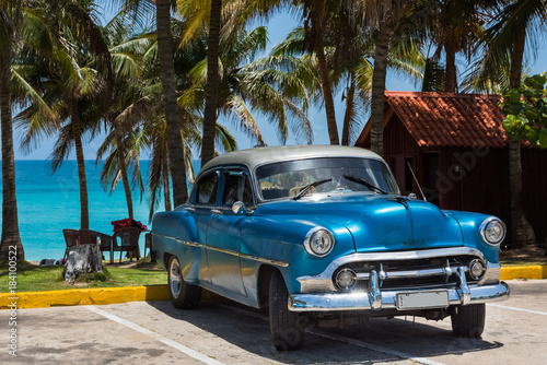 Amerikanischer blauer Chevrolet Oldtimer parkt am Strand unter Palmen in Varadero Cuba - Serie Cuba Reportage