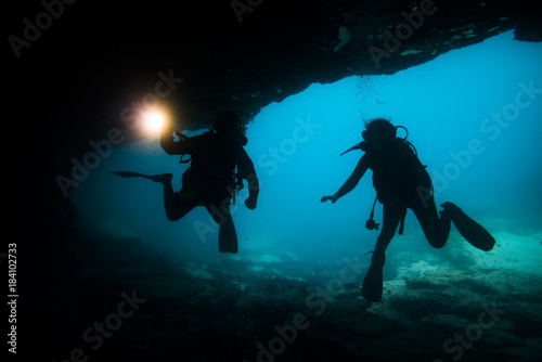 silhouette divers in a cave