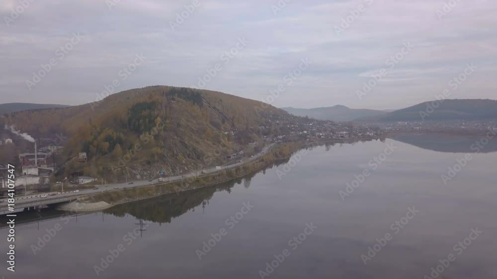 Panorama cars and truks moving on river bridge by city on mountain background Panorama cars and truks moving on river bridge by city on mountain background