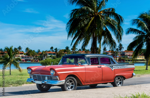 Amerikanischer roter Ford Oldtimer parkt am Strand unter Palmen in Varadero Cuba - Serie Cuba Reportage