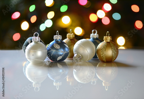 Ornaments and their reflections in front of Christmas tree lights