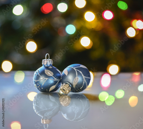 Pair of blue ornaments reflected in front of Christmas tree lights