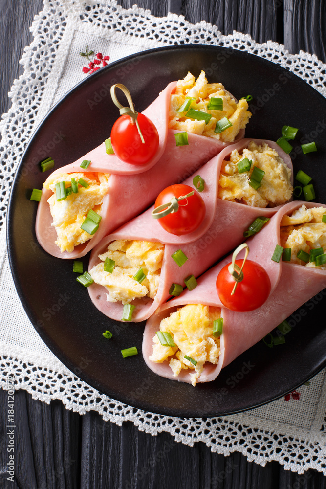 Beautiful breakfast: roll ham stuffed with omelets and tomatoes close-up. Vertical top view