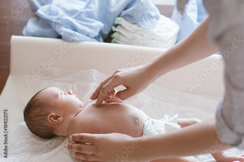 mother changes diapers to her newborn baby. motherhood daily routine. family lifestyle.