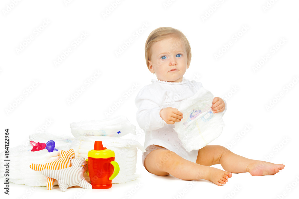 Caucasian kid with stacked diapers and toys isolated on white background Caucasian kid with stacked diapers and toys isolated on white background