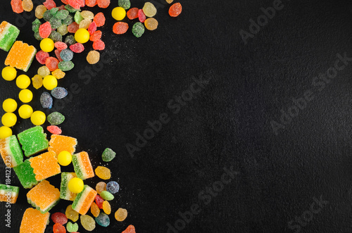 Brightly colored candies on a wooden table with copyspace, top view