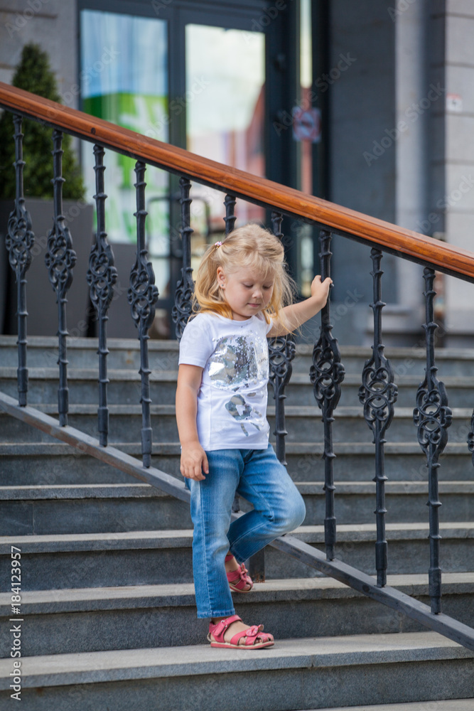 little blonde girl in jeans on the steps of the hotel little blonde girl in jeans on the steps of the hotel