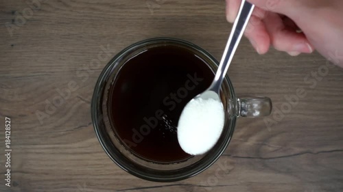 Woman is putting sugar in the cup of coffee