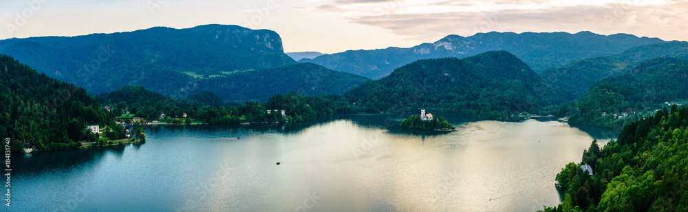 Evening views on the lake Bled with the famous Pilgrimage Church of the Assumption of Maria and Bled Castle and Julian Alps at background