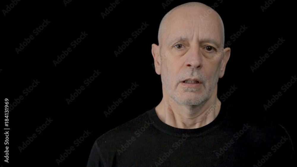 Portrait of a handsome natural disenchanted adult man with blue brown eyes and short hair, blowing through one's cheeks. Black background Portrait of a handsome natural disenchanted adult man with blue brown eyes and short hair, blowing through one's cheeks. Black background