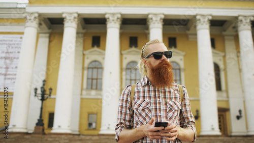 Bearded tourist man lost in city and using smartphone online map to find right directions