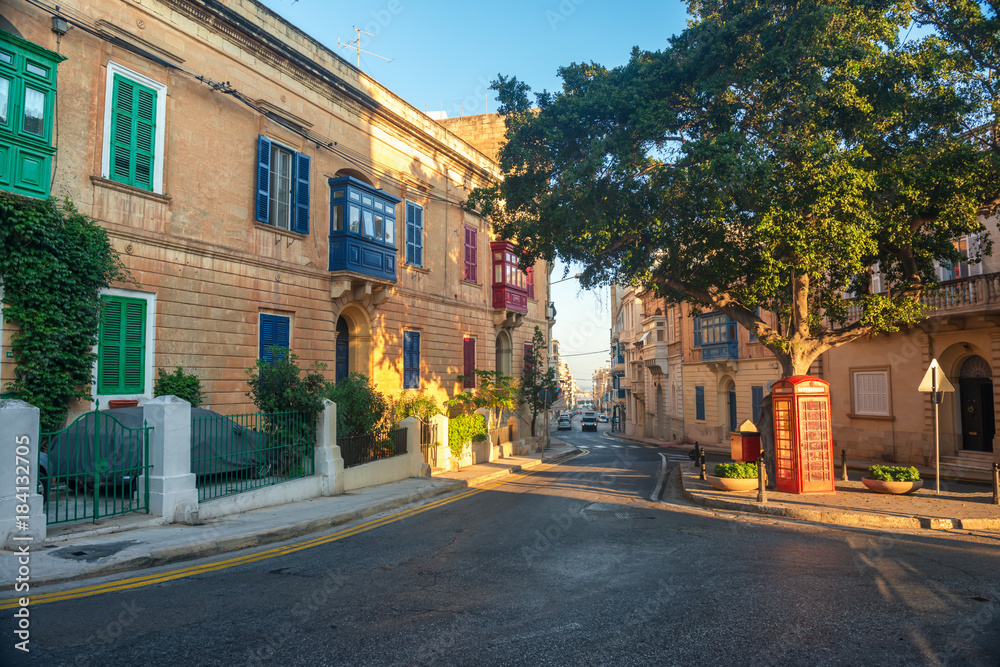 beautiful scene of maltese road in Sliema city in summer day and red telephone booth, Malta