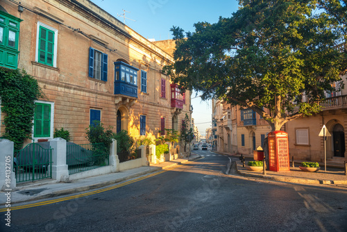 beautiful scene of maltese road in Sliema city in summer day and red telephone booth, Malta © Alisa
