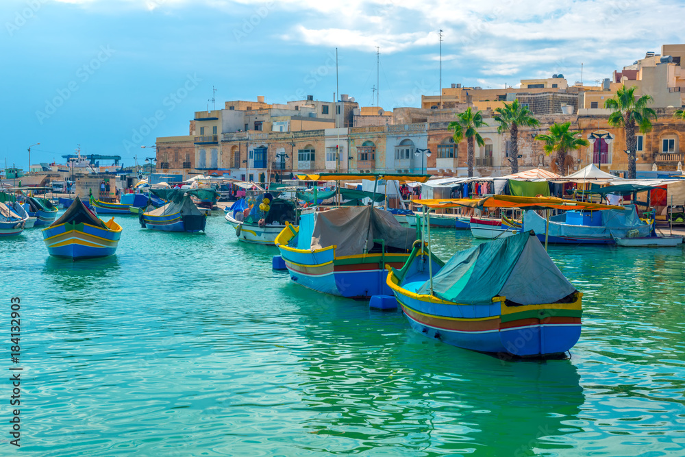 beautiful view of european harbor with village Marsaxlokk, market and traditional colorful Luzzu fishing boats, Malta