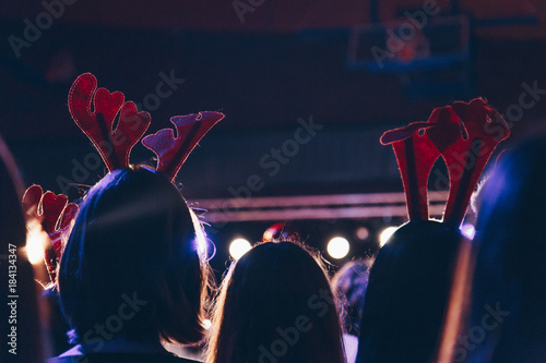 Fototapeta rear view of audience wearing christmas deer horns at a christmas concert