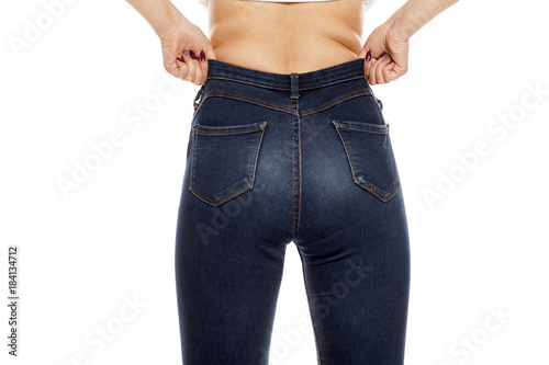 a young woman raising her jeans on white background