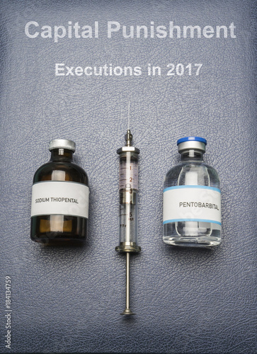 Vintage syringe and drugs used in lethal injection on a book of Capital Punishment executions in 2017, digital composition, conceptual image photo