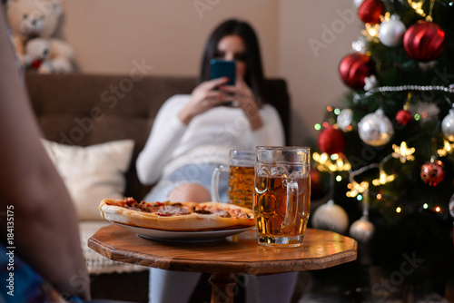 Girls eat pizza and talk in New Year s Night. Girls drink beer and eat pizza in front of Christmas tree