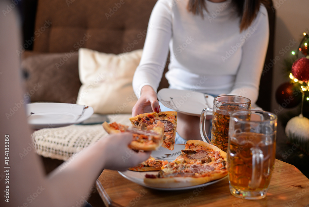 Woman takes a piece of pizza from a plate. Pizza on the table in New Year's Eve. Mixture pizza Italian food.