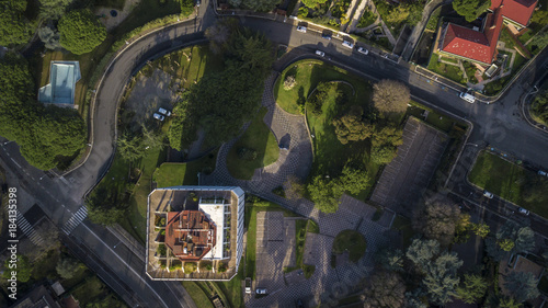 Vista aerea perpendicolare di un palazzo costruito dentro un parco che comprende anche ville private. La strada è nascosta dalla vegetazione e dagli alberi.