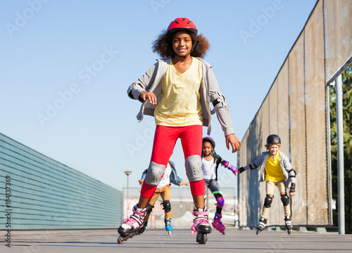 African girl rollerblading with friends at stadium