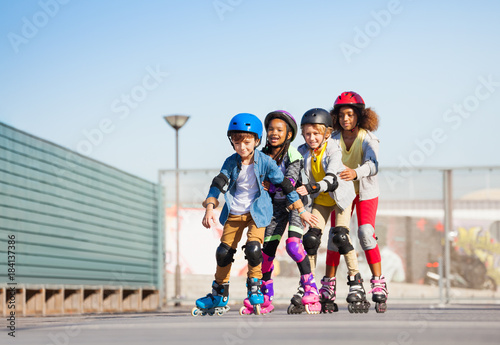 Happy kids rollerblading in a row outdoors