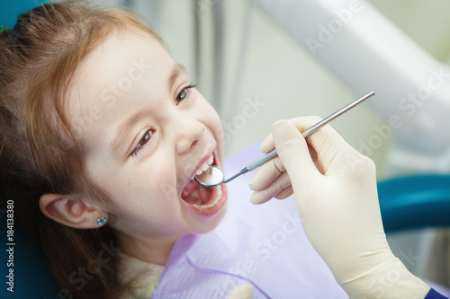 Happy child in dentist chair with napkin on chest