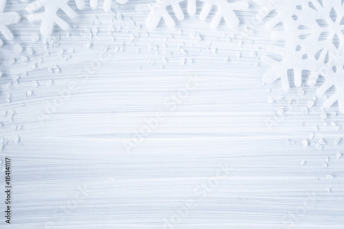 White artificial snowflakes on the cold, frosty wooden background. Mock up for holiday post card and Christmas offers as advertising or other ideas. Winter time concept. Empty place for a text. photo
