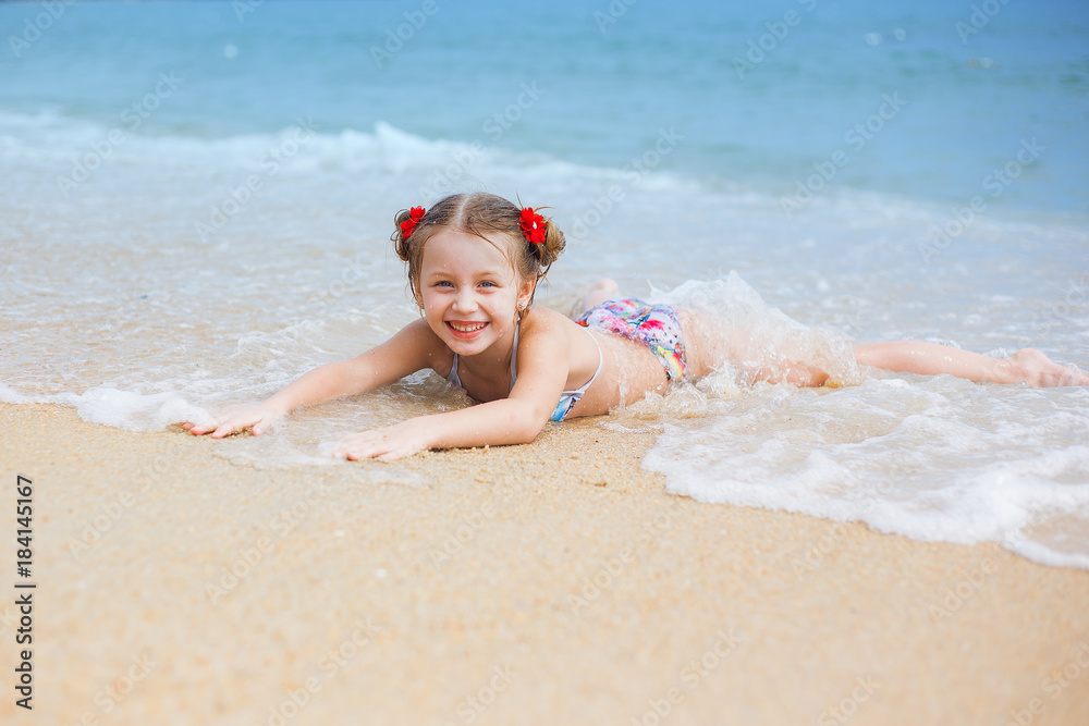 Happy girl with two pigtails floats lying on the sand by the sea, and enjoys playing Happy girl with two pigtails floats lying on the sand by the sea, and enjoys playing