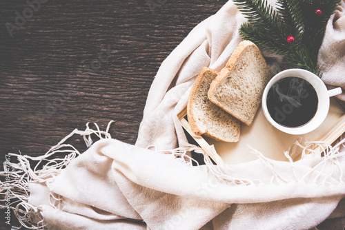Cup of coffee on rustic wooden serving tray in the cozy bed with blanket. Knitting warm woolen sweater in the winter weekend, top view, vintage tone, Lifestyle Concept.