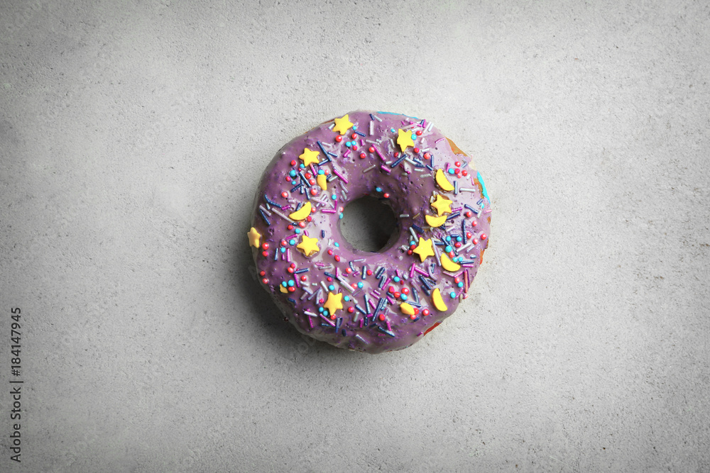 Purple donut with sprinkles on grey background Purple donut with sprinkles on grey background