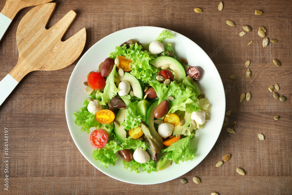 Plate with delicious vegetable salad on table, top view Plate with delicious vegetable salad on table, top view