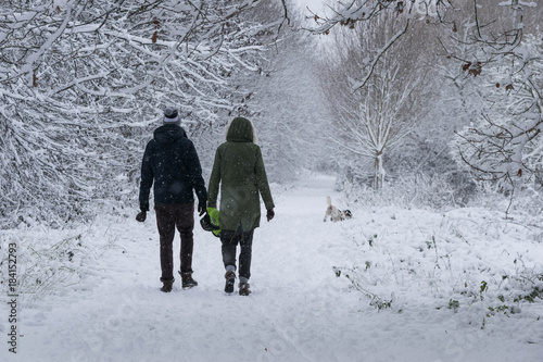 a couple walking their dog in the forest in a heavy snowfall day.