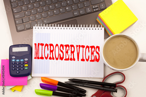 Word writing Microservices in the office with laptop, marker, pen, stationery, coffee. Business concept for Micro Services Workshop white background with copy space