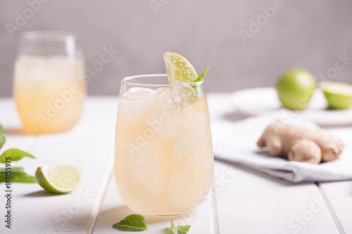 Fresh cocktail prepared with ginger beer, lime and ice. White table