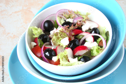 A salad of lettuce, olives, radishes, tomatoes, onions, cheese