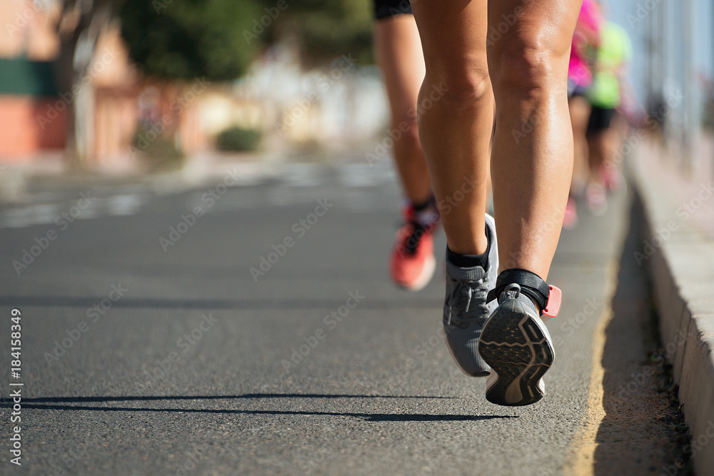 Marathon runners running on city road,detail on legs Marathon runners running on city road,detail on legs
