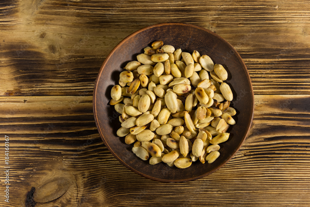 Roasted salted peanuts in plate on wooden table Roasted salted peanuts in plate on wooden table