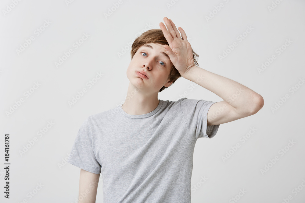 Tired fair-haired young man feels headahce after hard work, touches head with hand, stressed. Regretful caucasian guy has forgetful expression, tries to remember all necessary details Tired fair-haired young man feels headahce after hard work, touches head with hand, stressed. Regretful caucasian guy has forgetful expression, tries to remember all necessary details