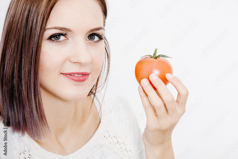 The girl holds a tomato. A young woman holds a tomato in her hands. The girl holds a tomato. A young woman holds a tomato in her hands.