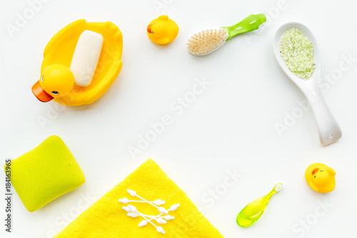 Baby bath set with yellow rubber duck. Soap, sponge, brushes, towel on white background top view copyspace
