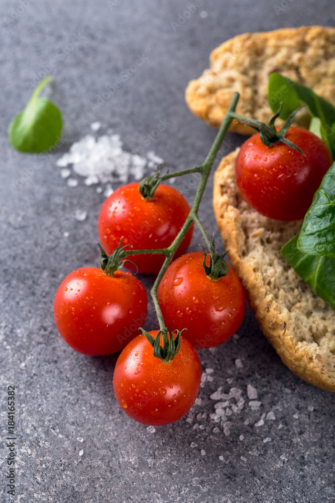 Cherry tomatoes, wholewheat rusks and corn salad on gray stone background. Healthy food concept. Cherry tomatoes, wholewheat rusks and corn salad on gray stone background. Healthy food concept.