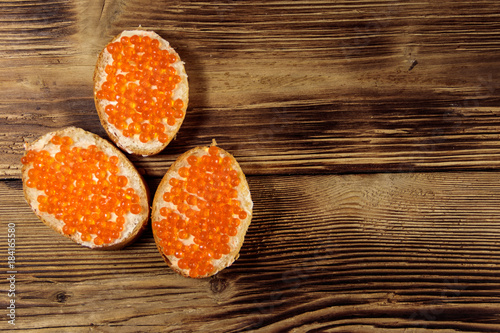 Sandwiches with butter and red caviar on wooden table