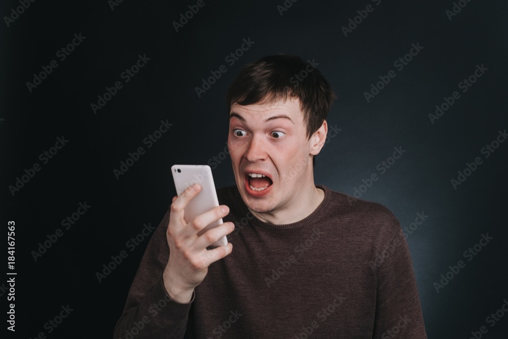 Guy I saw on the screen of a mobile phone shocking news, closeup portrait in Studio