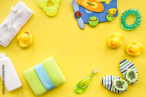 Baby care with bath set, ducklings and towel on yellow backgroun
