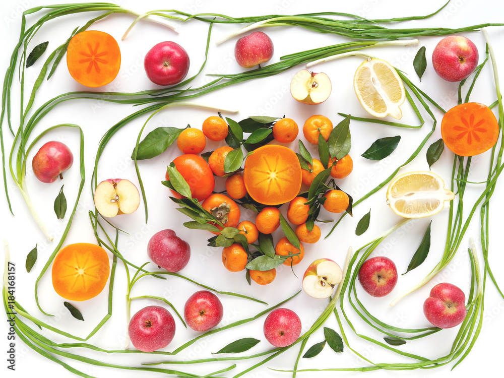 Creative flat layout of fruit, top view. Sliced lemon, red apples, persimmon, tangerine, green onion, green leaves isolated on white background. Food wallpaper, composition pattern of fresh fruits. Creative flat layout of fruit, top view. Sliced lemon, red apples, persimmon, tangerine, green onion, green leaves isolated on white background. Food wallpaper, composition pattern of fresh fruits.